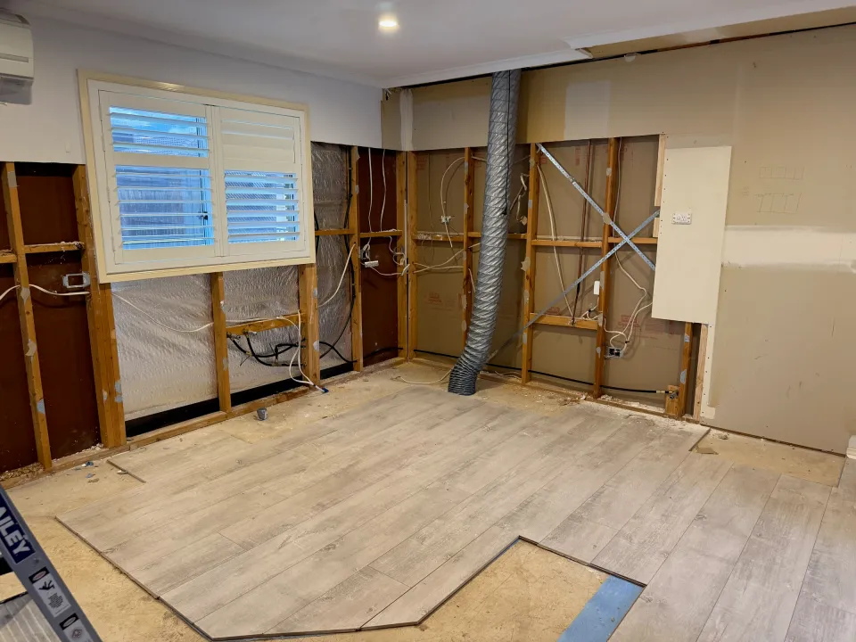Point Cook kitchen during strip-out, with exposed wall framing and the existing shuttered window