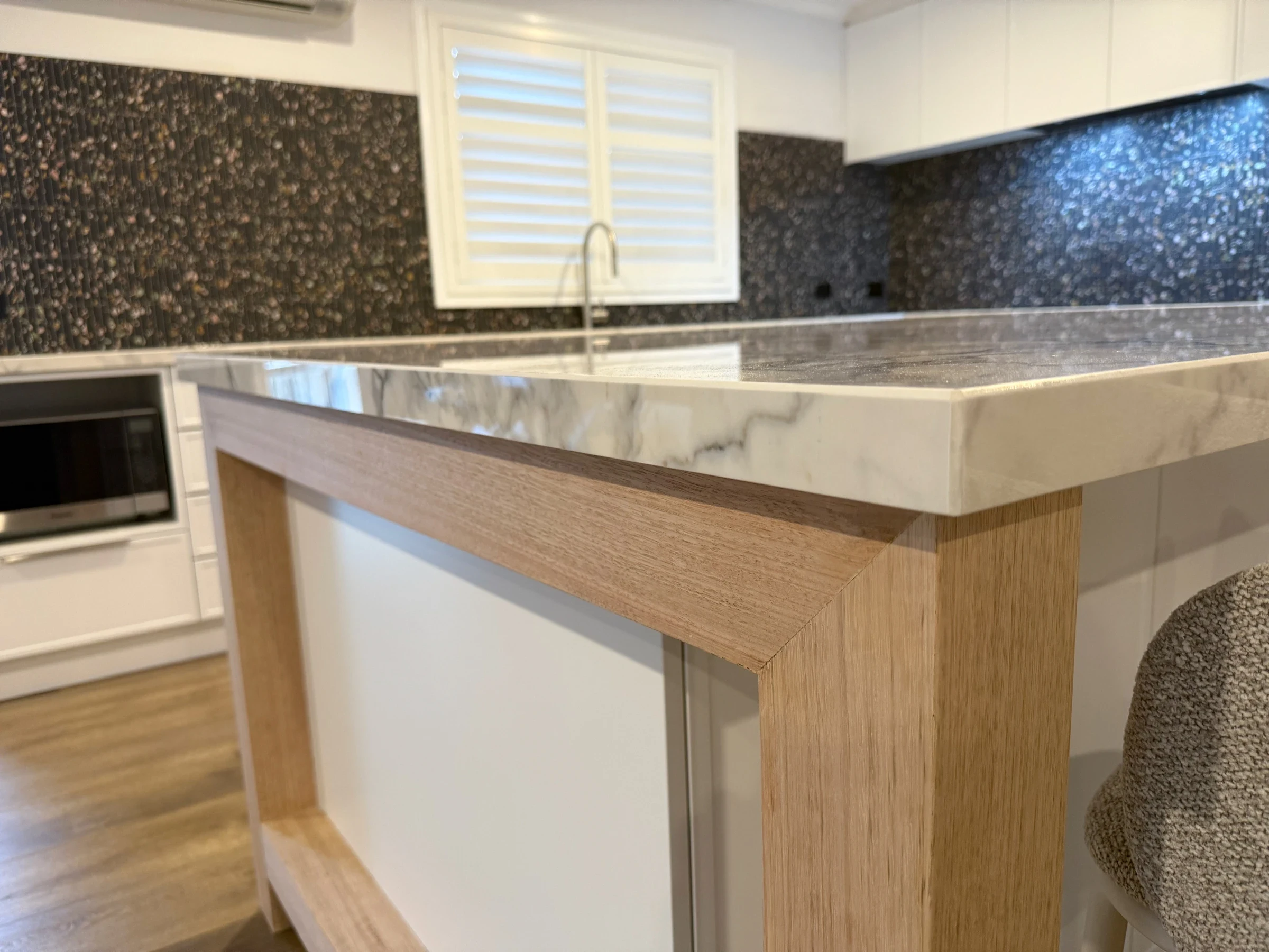 Stone benchtop and timber island frame in the completed Point Cook kitchen