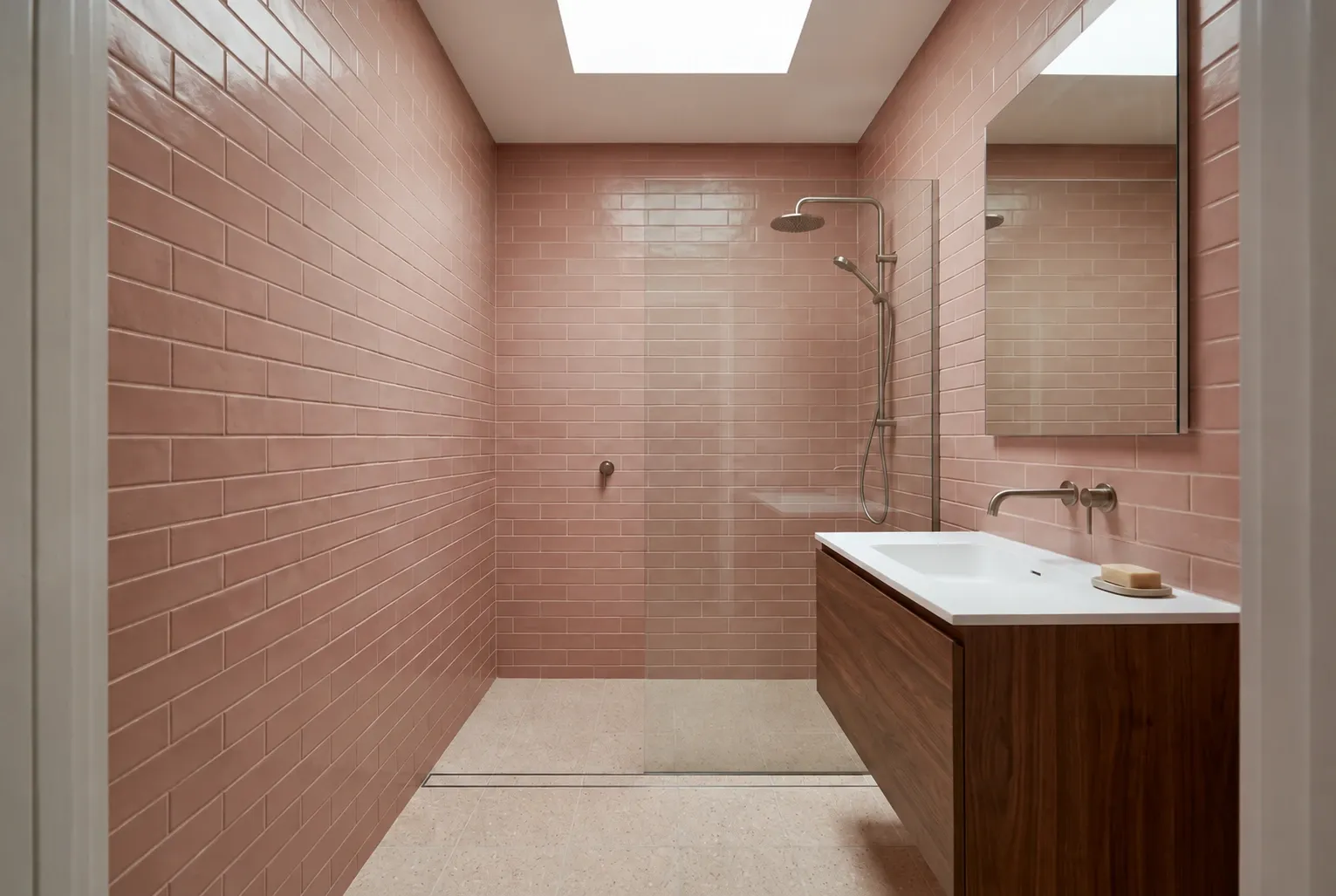 Compact bathroom inspiration with muted rose tiles, walnut vanity and a glass shower