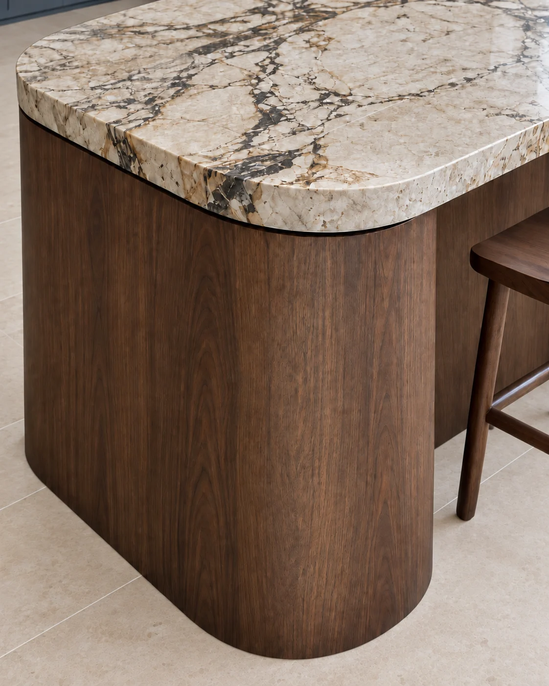 Close detail of the curved dark-oak island end and cream stone benchtop with dark veining