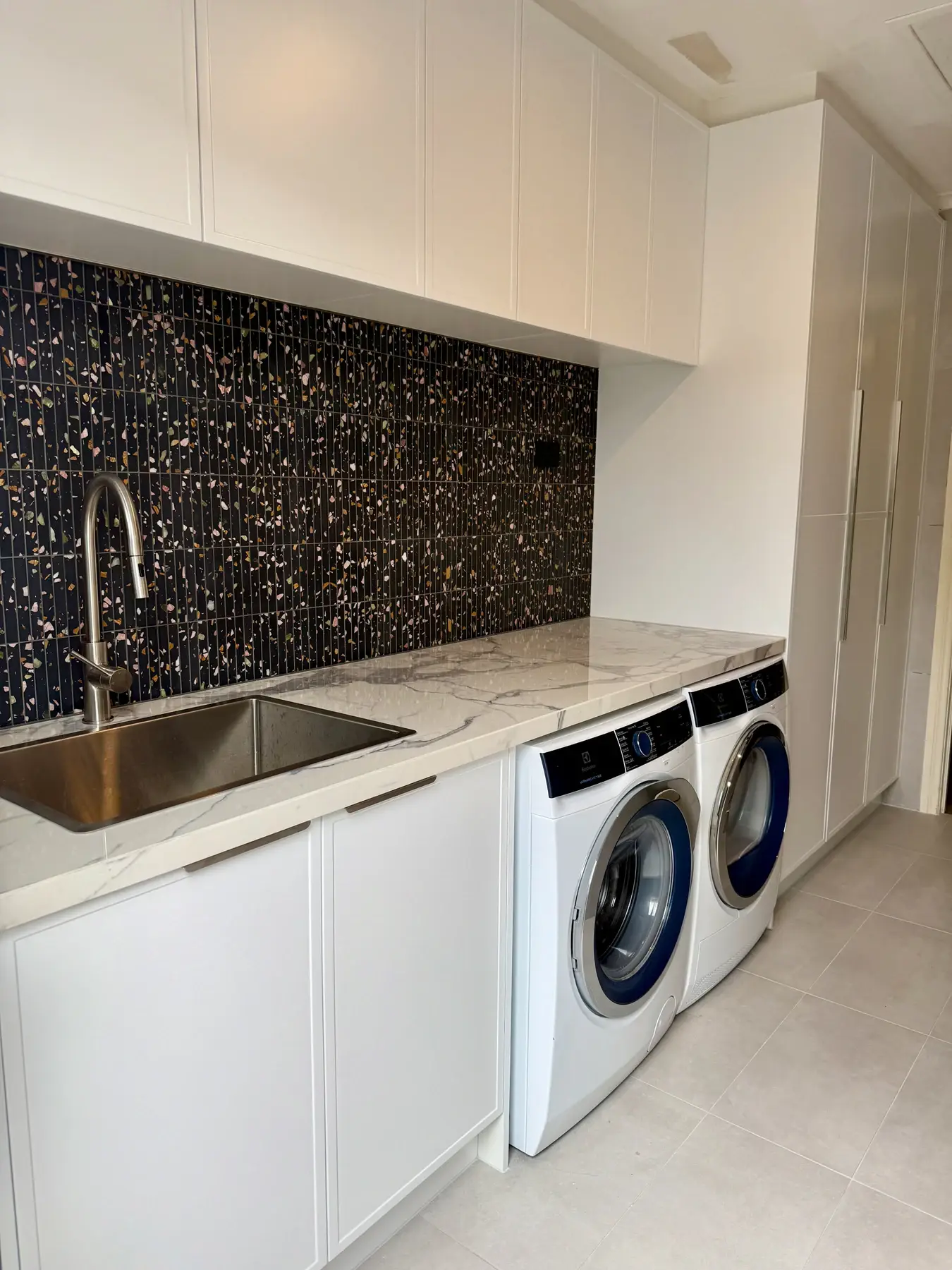 Completed Bluestone laundry with a mosaic splashback and under-bench appliances