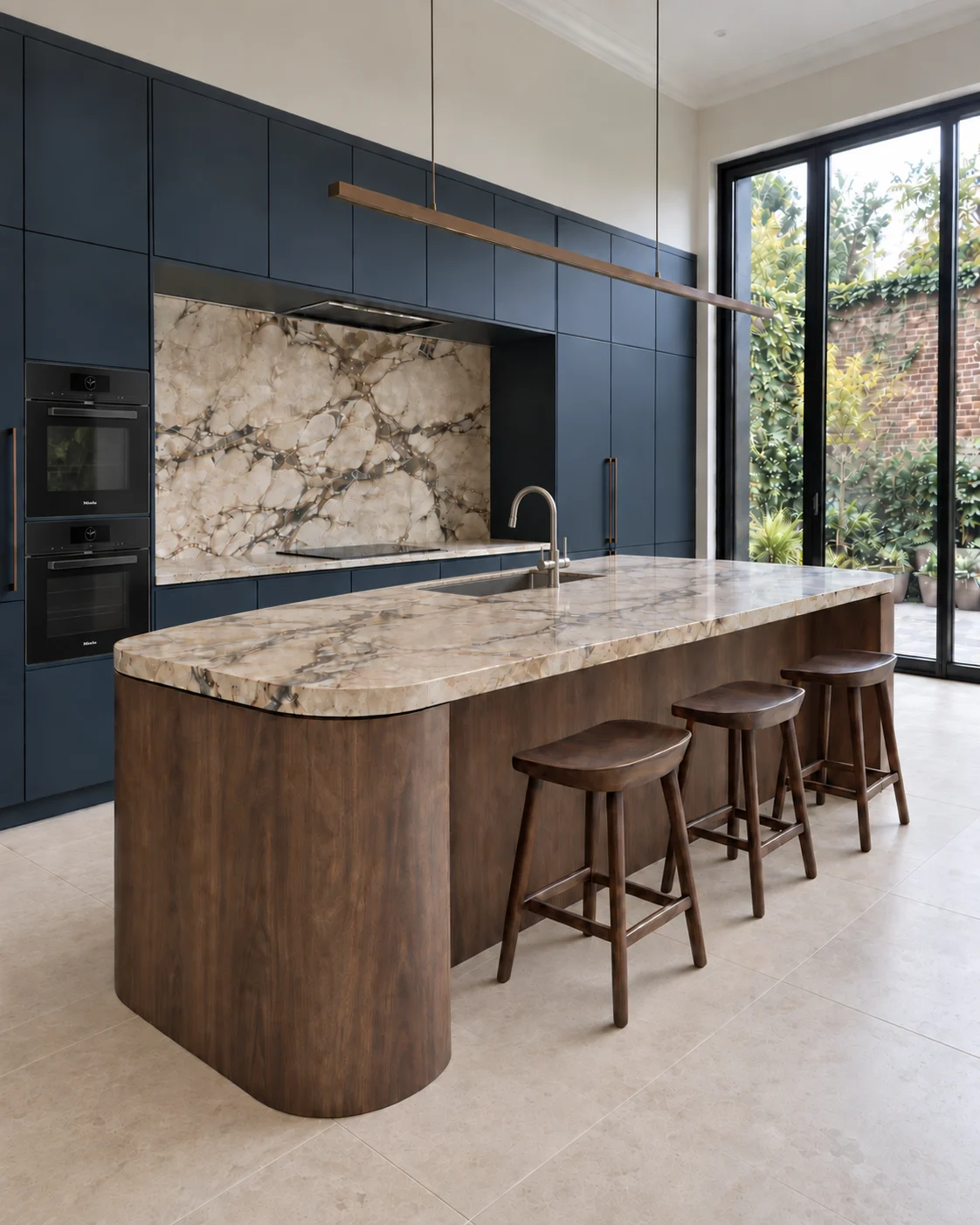 Deep-blue kitchen cabinetry with a curved dark-oak island, veined stone surfaces and courtyard glazing