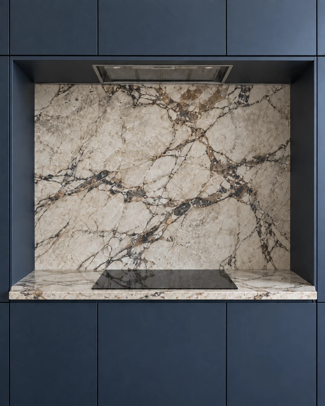 Veined stone cooking niche framed by deep-blue cabinetry with an induction cooktop and concealed extractor