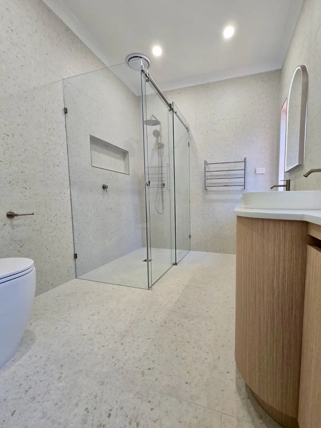 The shower in a completed Bluestone bathroom, with a built-in niche and matching wall and floor finishes.